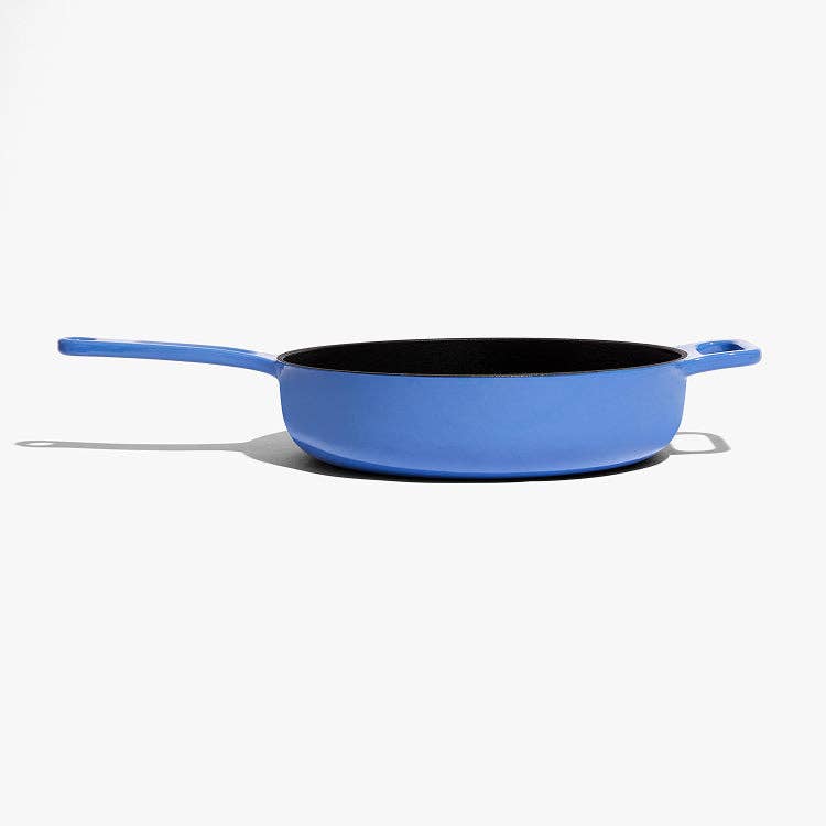 A blue enameled cast iron skillet with a black interior, shown from a side angle on a light gray background.
