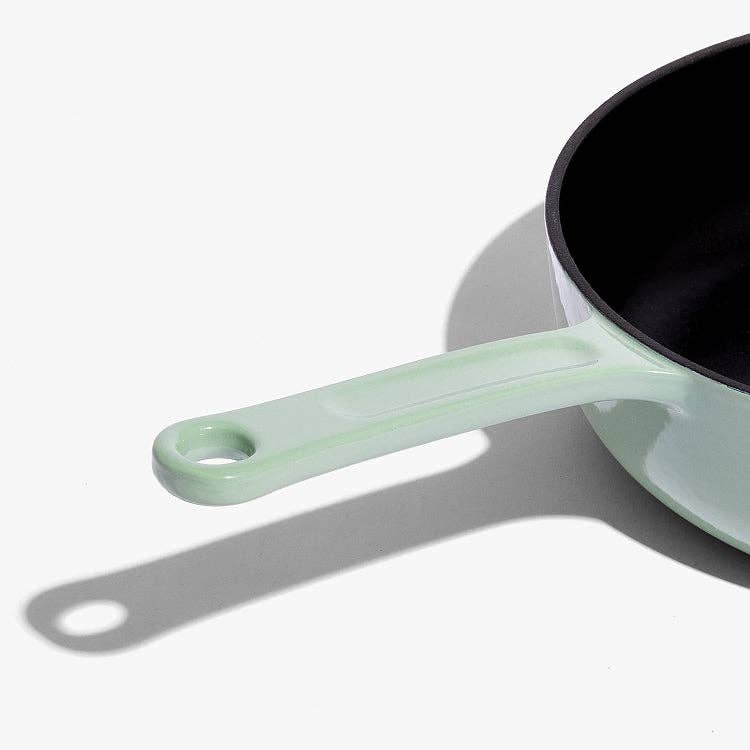 Light green frying pan with black interior on a white background