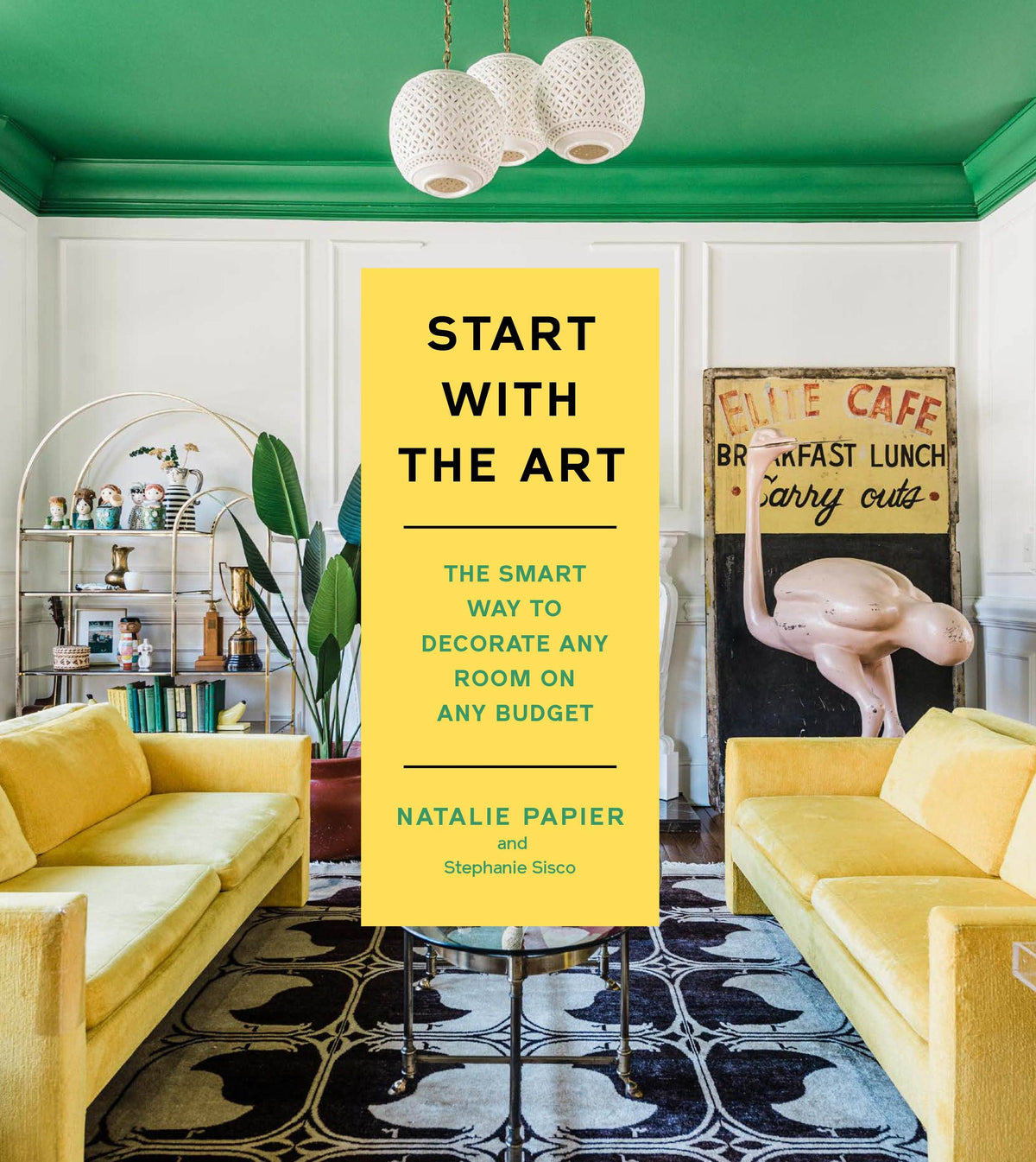 Book titled 'Start with the Art' in a stylish living room with yellow couches and green walls.