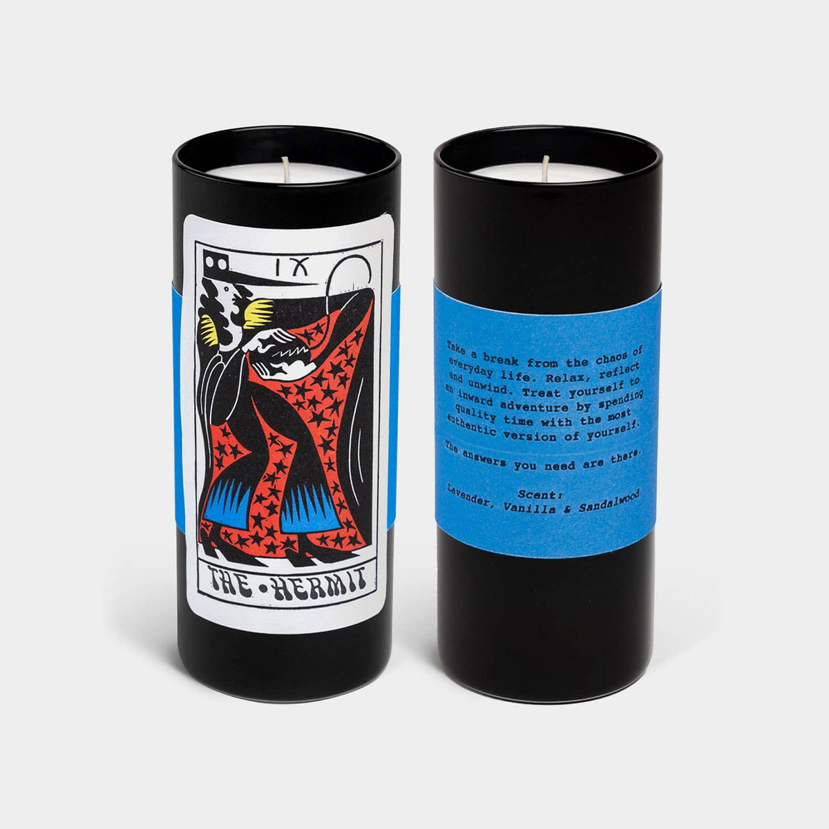 Two candles in black cylindrical containers with tarot card design and text on a white background