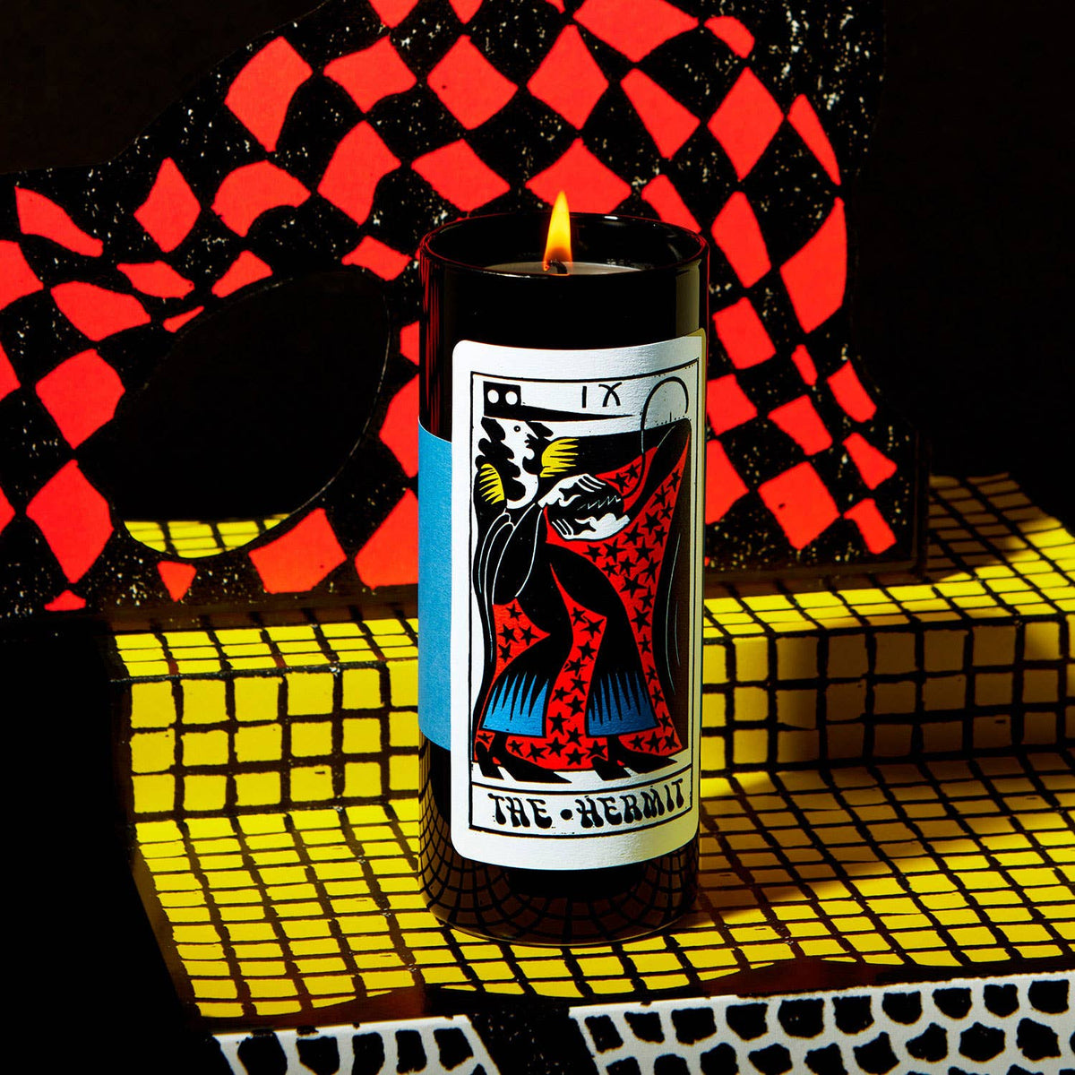 Candle with Tarot card design on a checkered background