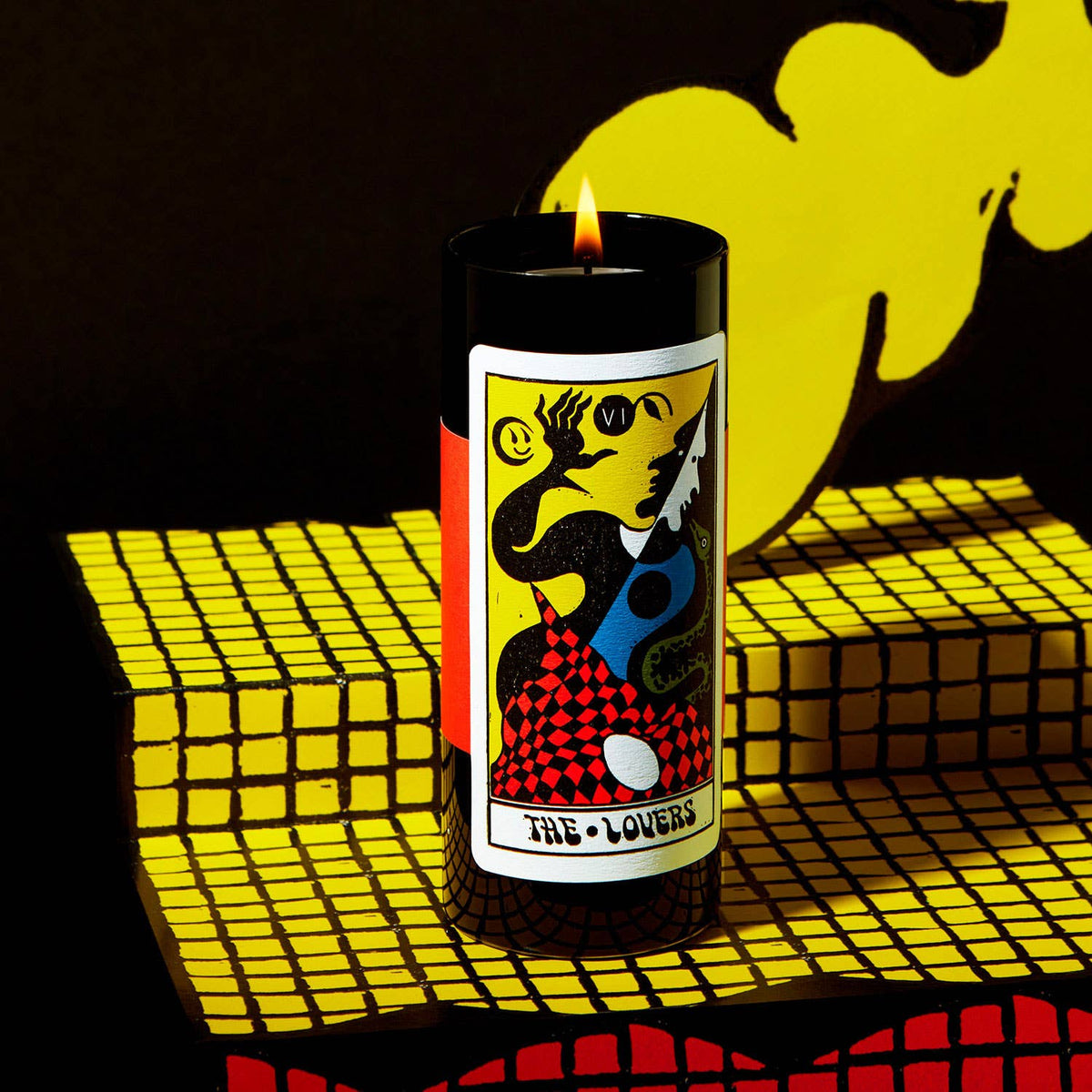 Candle with tarot card design on a yellow and black checkered surface