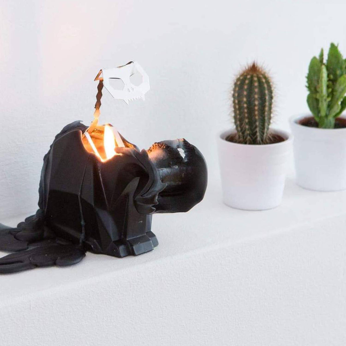 Black lamp shaped like a character with a white background and cacti.