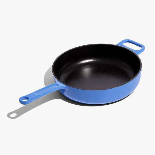 Black frying pan with blue handles on a white background