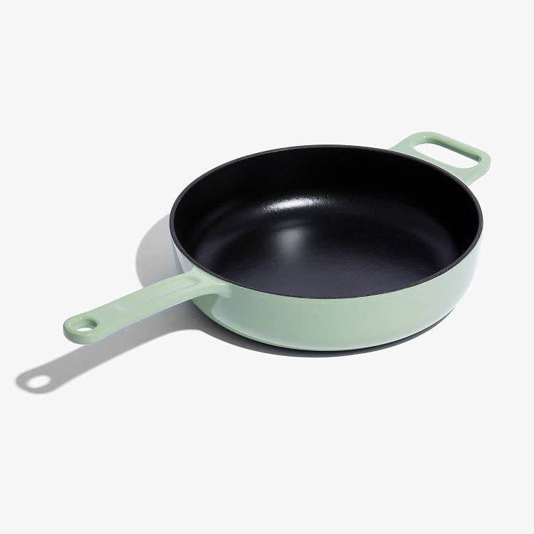 Green frying pan with a black interior on a white background