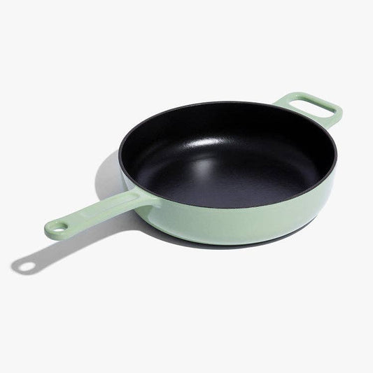 Green frying pan with a black interior on a white background