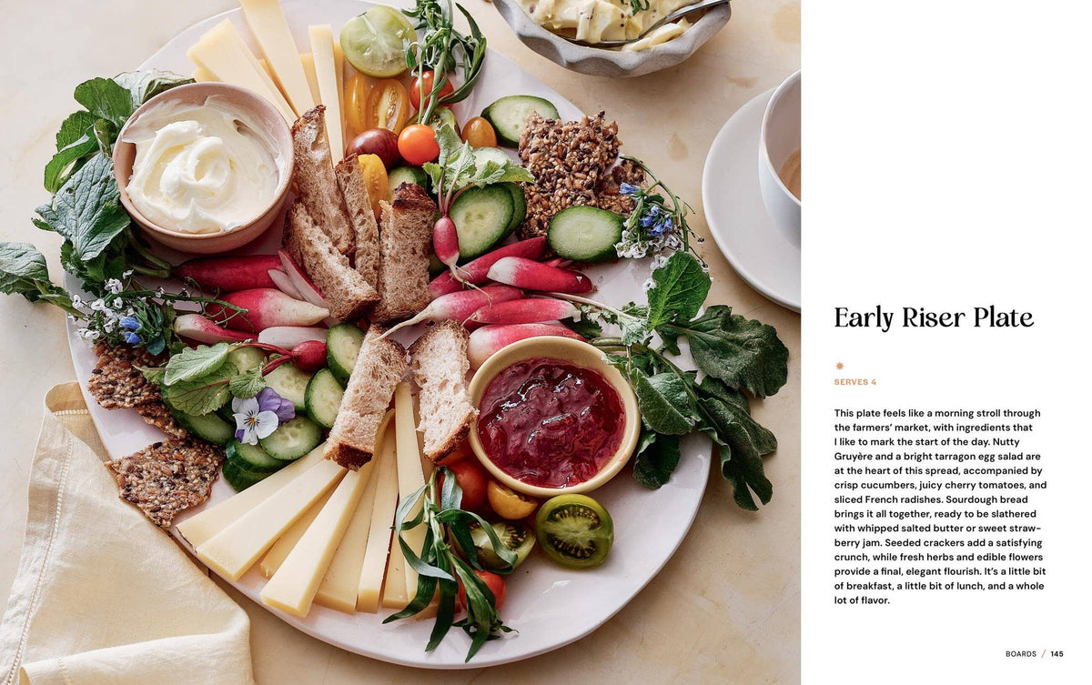 Platter of assorted foods including bread, cheese, and vegetables with a side of dip on a white surface.