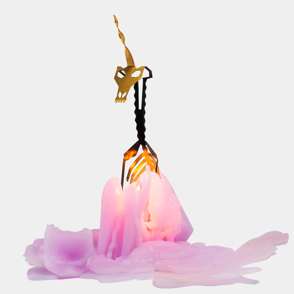 Decorative item with a gold unicorn horn on a pink cloud-like base against a white background