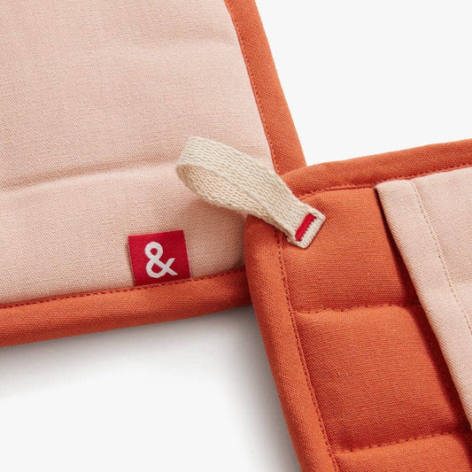 Close-up of a product with a red label featuring a white ampersand symbol on a light background.