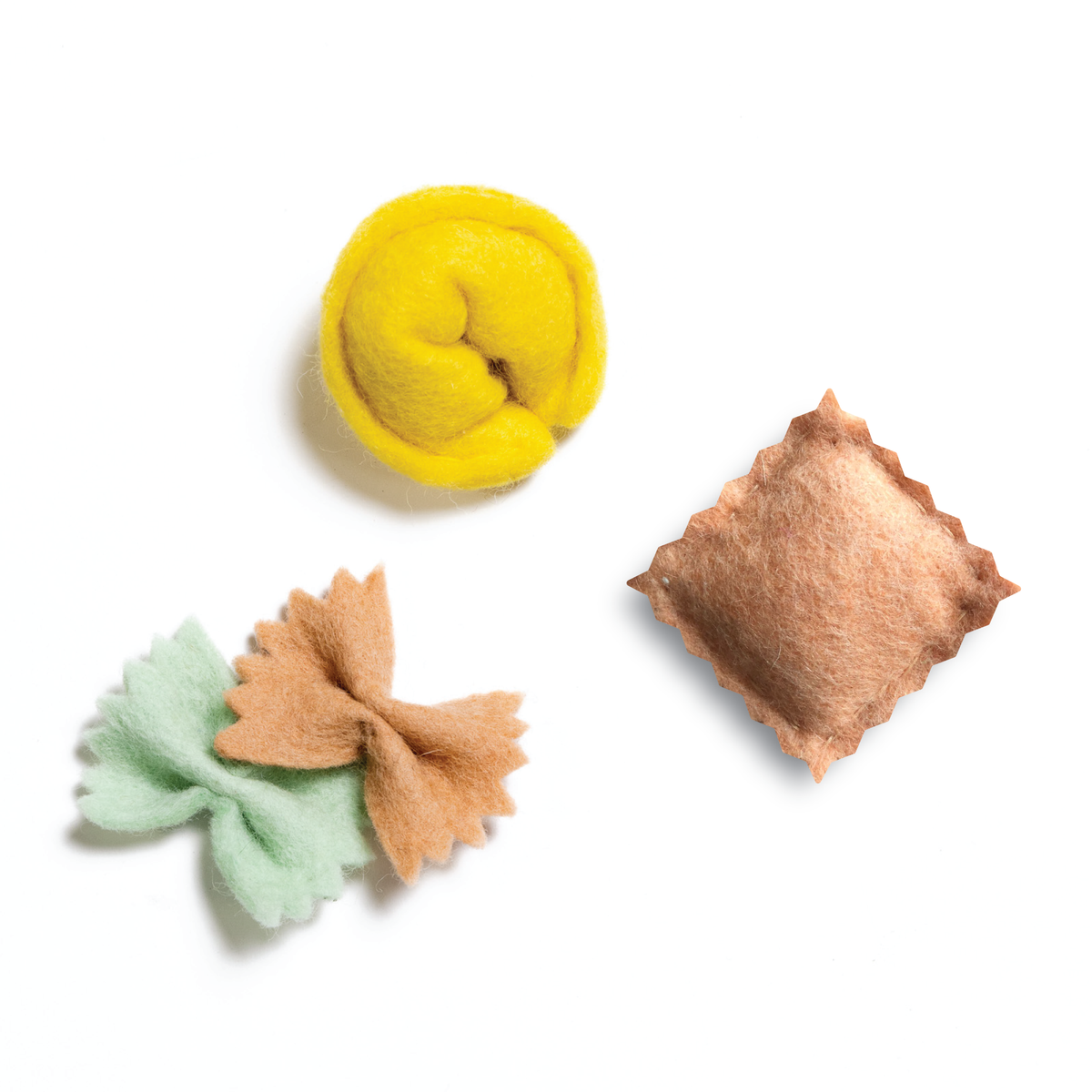 Three felt food items on a white background: a yellow ball, a brown square, and a green and brown bow.