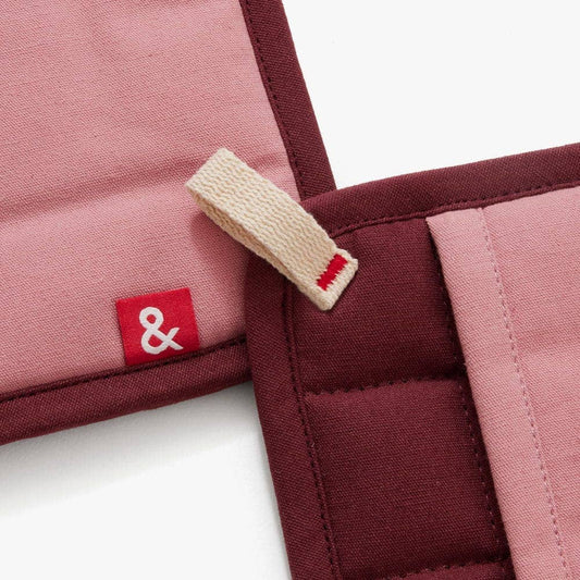 Close-up of a maroon and pink fabric product with a red label featuring a white ampersand symbol.