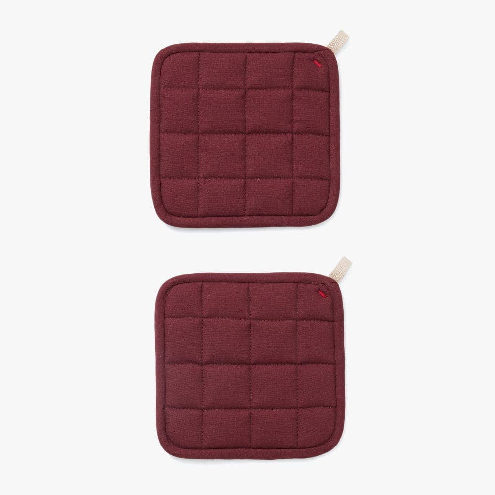 Two maroon quilted pot holders on a white background