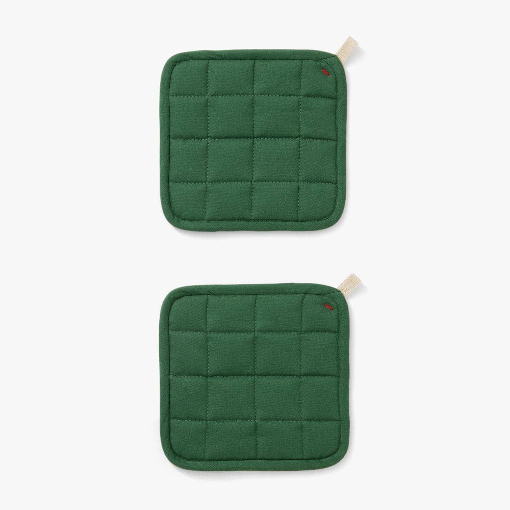 Two green quilted pot holders on a white background
