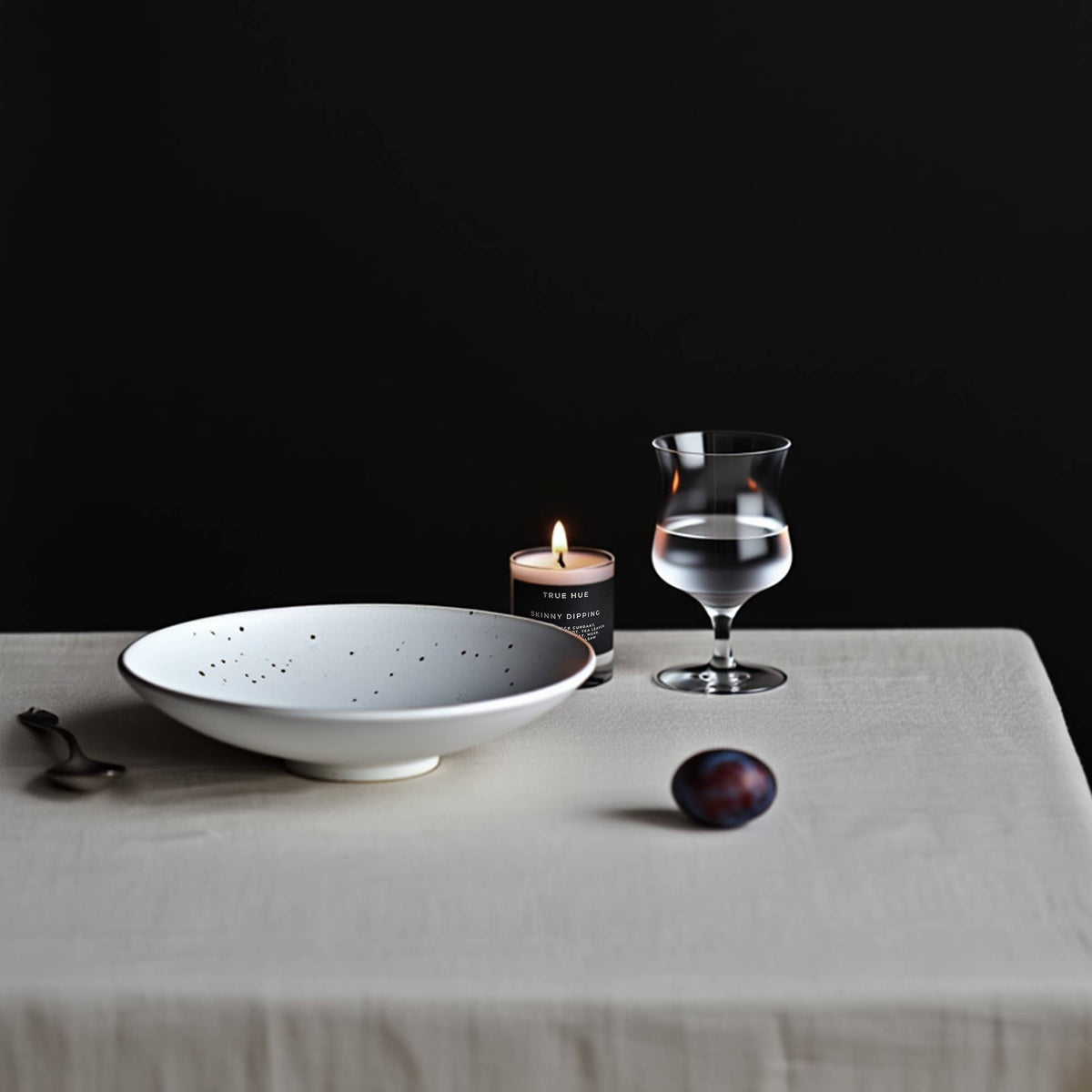 Table setting with a bowl, candle, and glass on a dark background