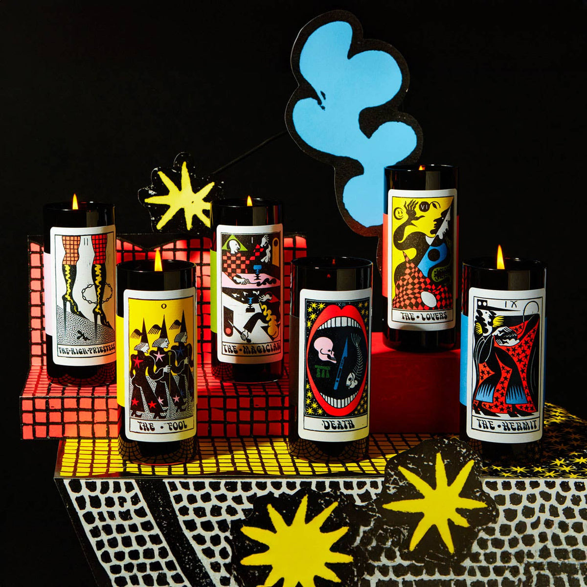 Collection of tarot-themed candles on a dark background with decorative elements.