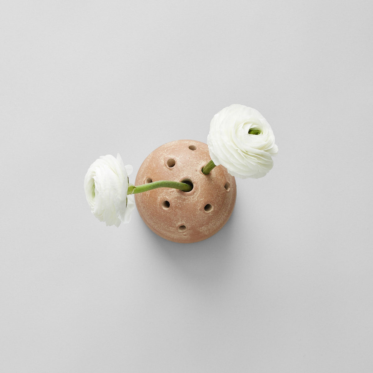 Small stone with two white flowers on a light gray background