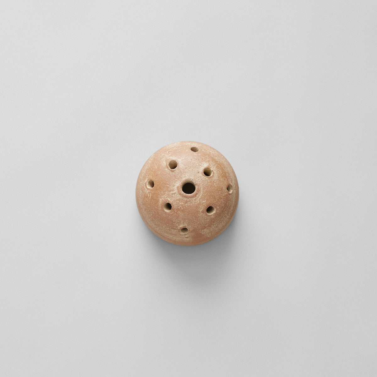 Round ceramic object with holes on a light gray background