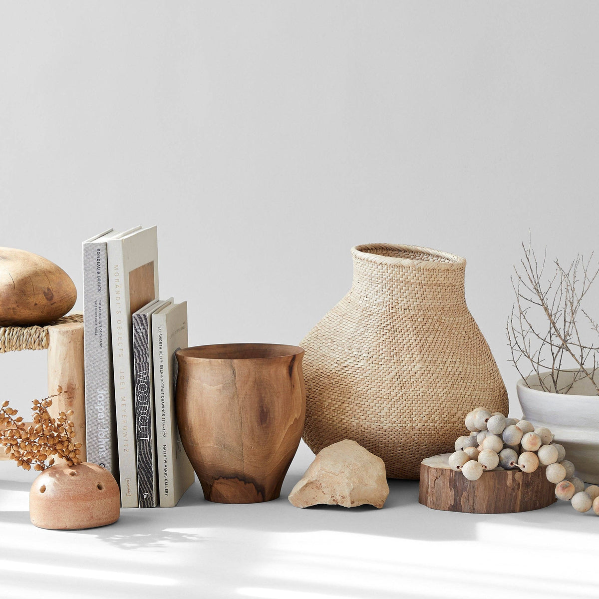 Decorative vases and other objects with dried plants on a white background.