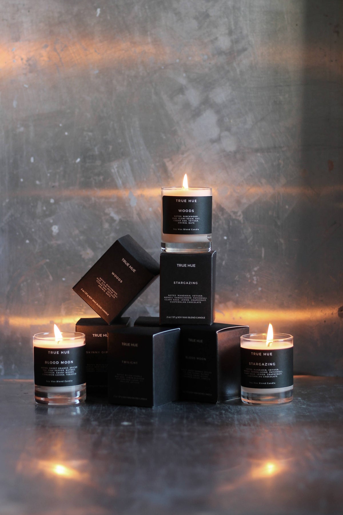 Candle and packaging set on a metallic surface with a warm glow