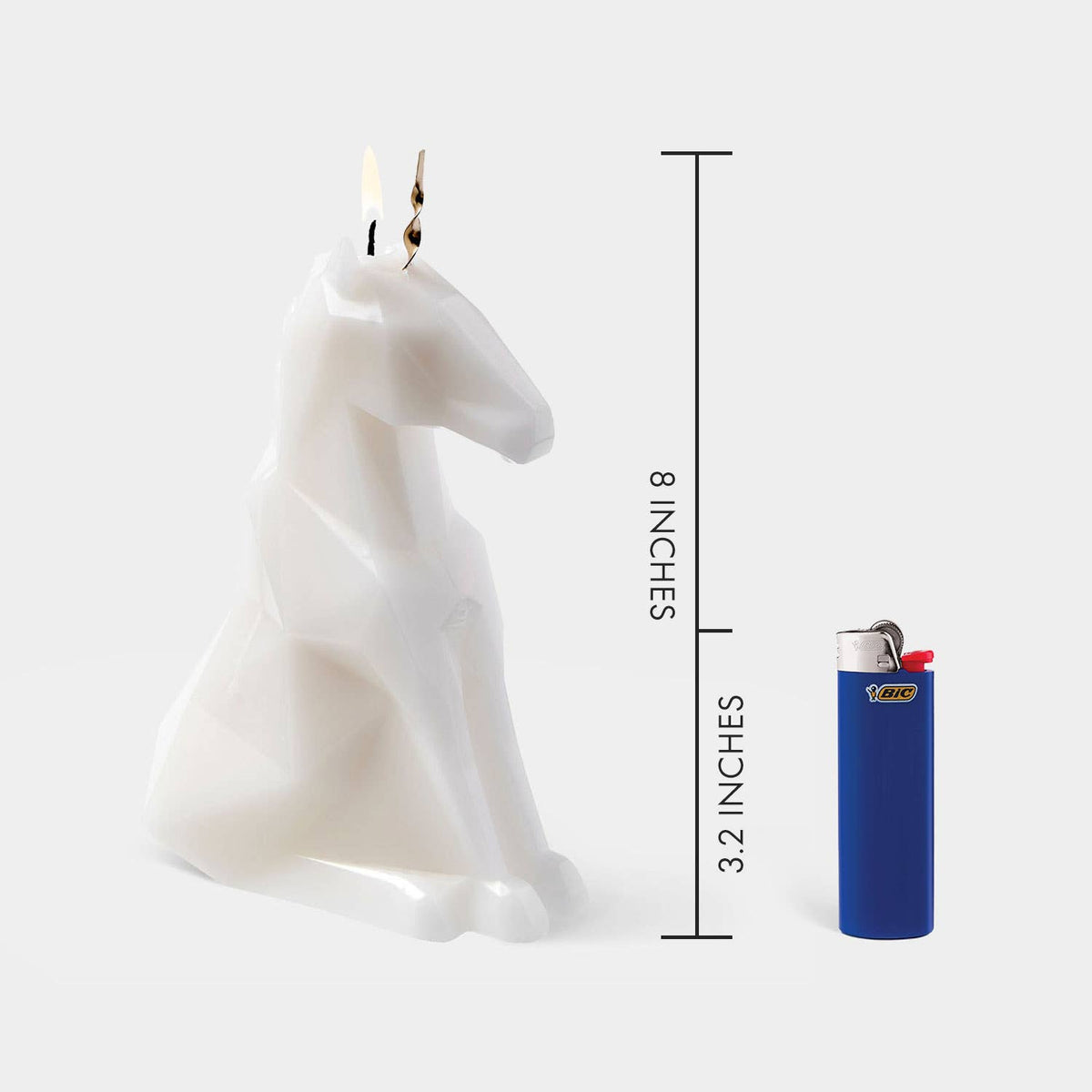White horse-shaped candle with dimensions indicated by a lighter for scale on a white background